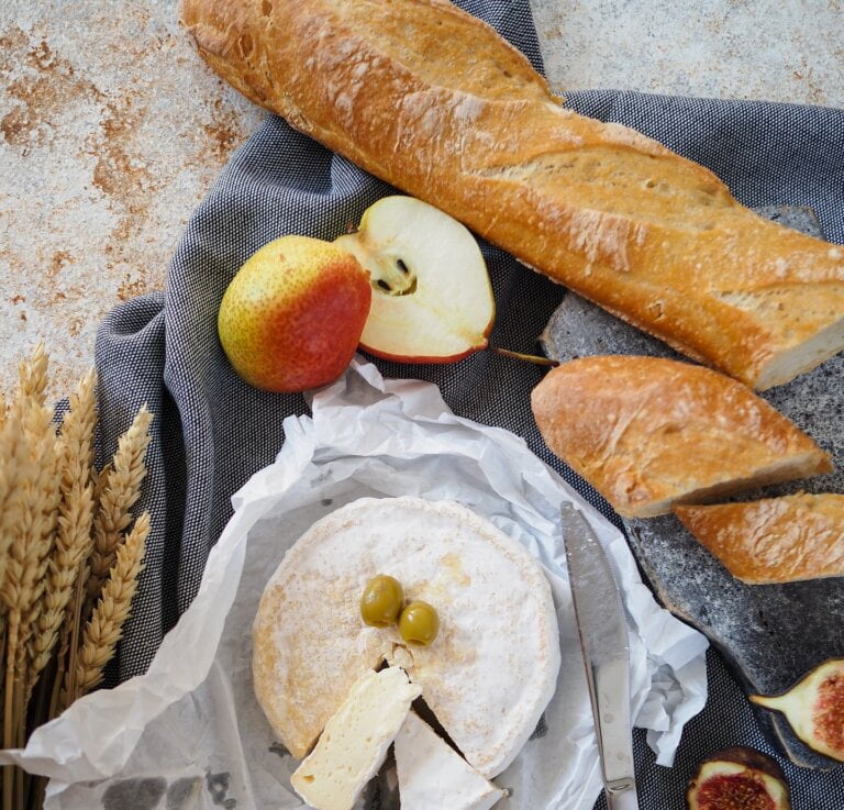 Artisan French Baguette, Cheese, Knife, And Grains Arranged On A Table