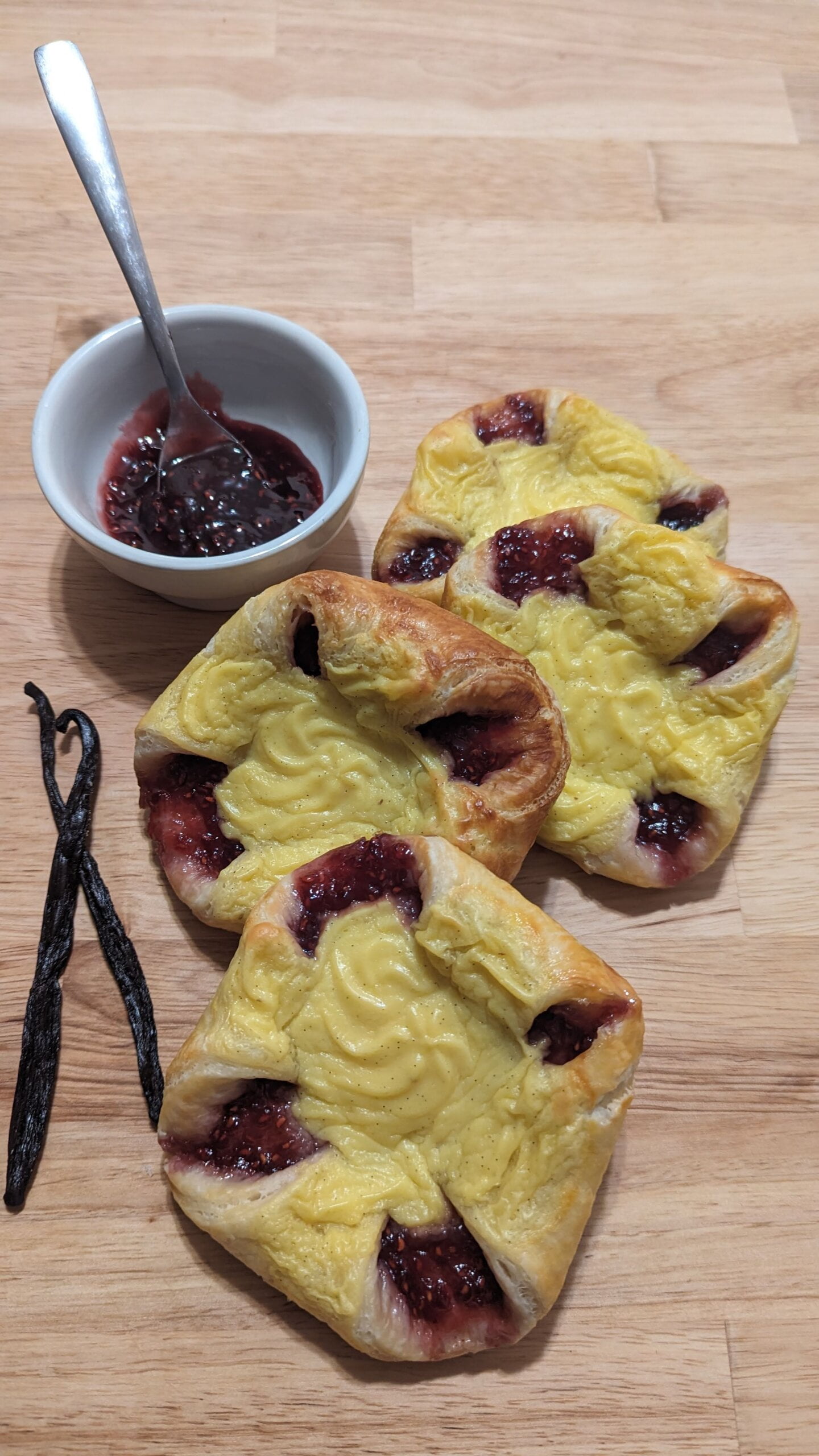 This picture shows 4 sweet vanilla raspberry danish with 2 vanilla beans