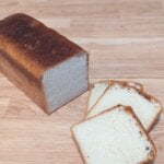 a loaf of bread and slices of bread on a wooden surface