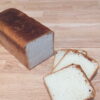 A Loaf Of Bread And Slices Of Bread On A Wooden Surface