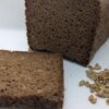 Freshly baked deep earth rye black bread (pumpernickel) with a rich, dark color and dense texture, made with 100% rye flour and sunflower seeds for a hearty, flavorful taste