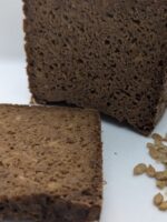 Freshly baked deep earth rye black bread (pumpernickel) with a rich, dark color and dense texture, made with 100% rye flour and sunflower seeds for a hearty, flavorful taste