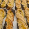Close-Up Of A Golden Cheese Twist Pastry Made With Emmentaler Cheese, Topped With Sesame And Poppy Seeds.