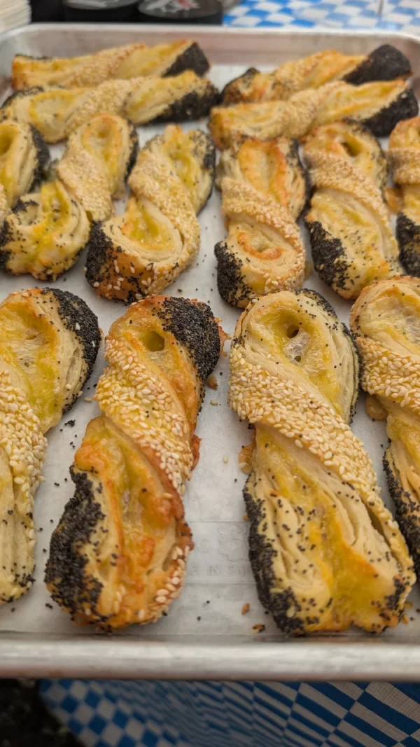 Close-Up Of A Golden Cheese Twist Pastry Made With Emmentaler Cheese, Topped With Sesame And Poppy Seeds.